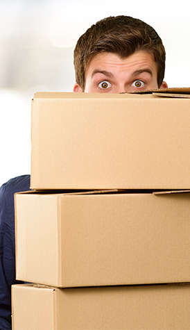 Mensch blickt über einen Stapel mit Kartons