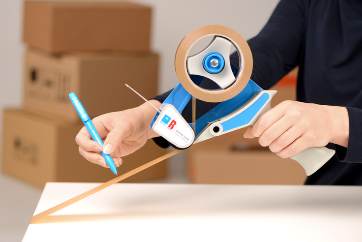 Person die ein Paket mit einem Handabroller verklebt