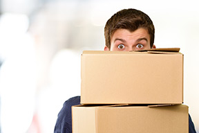 Mensch blickt über einen Stapel mit Kartons